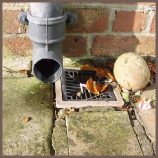 Oxford surveyors. Photograph of a downpipe where the discharge misses the drain